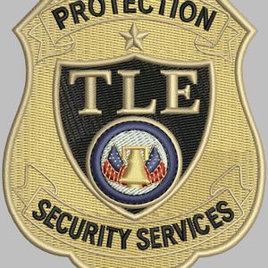 May include: Embroidered security badge with the words "PROTECTION" and "SECURITY SERVICES". The badge features the letters "TLE" and a central emblem with American flags and a bell. The badge is gold and black.