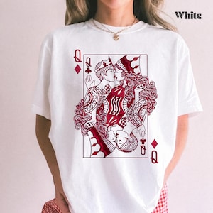 May include: White t-shirt featuring a Queen of Hearts playing card design. The graphic depicts two women kissing, with the card's suit symbols and the word "White" printed on the shirt.