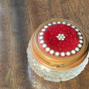 May include: A vintage glass and metal trinket box with a red velvet interior and a white and gold decorative lid.