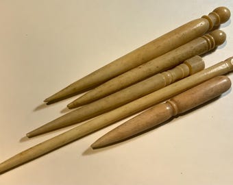 May include: Five antique bone crochet hooks, with varying lengths and rounded tips. The hooks are made of a light beige bone and have a smooth, polished finish.