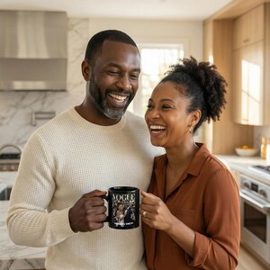 May include: A black coffee mug with the word "VOGUE" printed on it, along with a photograph of a couple. The mug is held by a person in a kitchen setting. The couple is smiling.