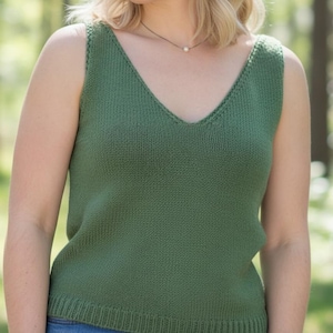 May include: A green knitted vest top with a V-neck. The sleeveless top is a solid colour and appears to be made of a soft, textured yarn. The background is a blurred outdoor scene with trees.