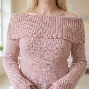 May include: A light pink off-the-shoulder sweater with long sleeves. The sweater features a ribbed collar and cuffs, and a plain knit body. The soft, muted color and simple design create a cozy and elegant look.