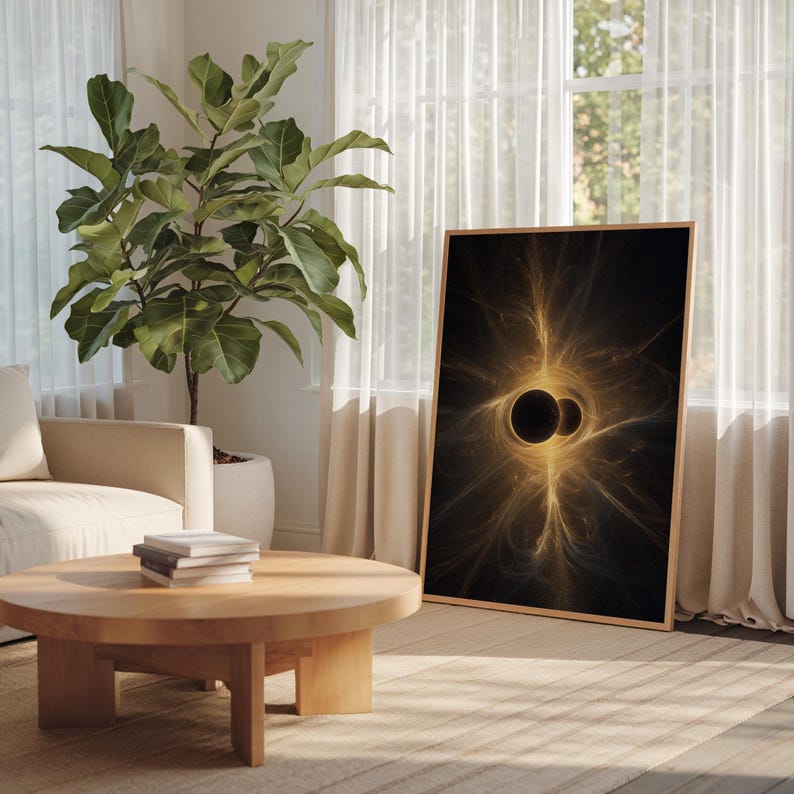 May include: A framed art print featuring a black and gold abstract design. The artwork depicts two dark circles surrounded by radiating golden lines, creating a celestial or cosmic theme. The frame is a light wood color.