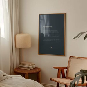 May include: A rectangular wall art print in a thin gold frame featuring a dark charcoal background with the white text "Soften here." followed by several lines of smaller white text and a small white circular icon at the bottom centre.