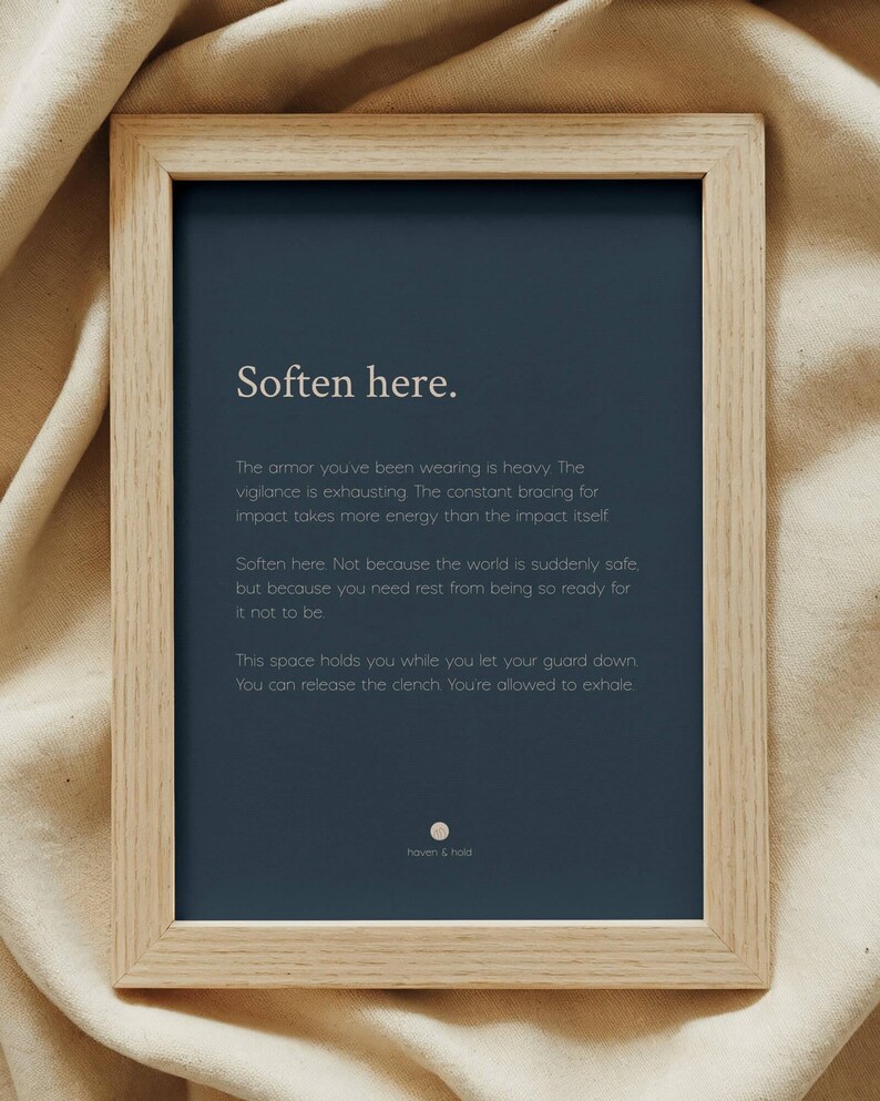 May include: A rectangular light wood frame containing a dark blue print with the white text: Soften here. The armour you've been wearing is heavy. The vigilance is exhausting. The constant bracing for impact takes more energy than the impact itself.
