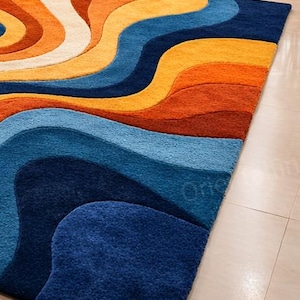 May include: A vibrant rug with a flowing, wave-like pattern in shades of orange, yellow, blue, and cream. The rug's design is a modern, abstract pattern, adding a vibrant touch to any room. The rug's design is a modern, abstract pattern.