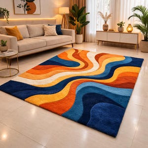 May include: A large, rectangular rug with an abstract design. The rug has flowing, wavy patterns in shades of blue, orange, yellow, and white. The rug is placed on a light-coloured floor in a living room setting.