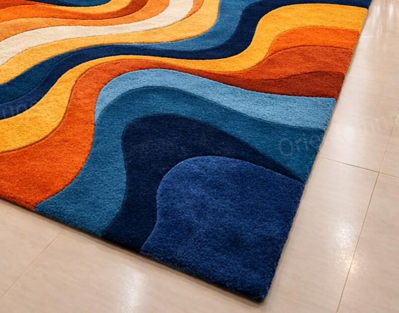May include: A patterned rug with a wave-like design in shades of orange, yellow, white, and blue. The rug's design creates a sense of movement and adds a modern touch to any space. The rug is a statement piece.