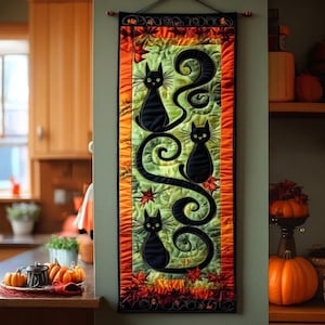 May include: A Halloween-themed wall hanging featuring three black cat silhouettes with green eyes, set against a green and orange background. The cats are connected by swirling black lines, with autumn leaves and a decorative border. The wall hanging is approximately 30 inches long.