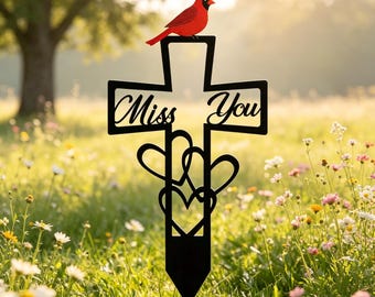 Estaca conmemorativa de metal con forma de cruz cardenal, lápida con la inscripción "Te extraño" y detalles en forma de corazón.