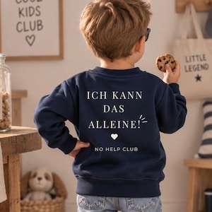 Könnte beinhalten: Ein dunkelblaues Langarm-Sweatshirt mit weißem Aufdruck auf der Rückseite, der ICH KANN DAS ALLEINE! lautet, ergänzt durch ein kleines Herzsymbol und den Text NO HELP CLUB darunter. Das Sweatshirt wird mit einer hellblauen Jeans und weißen Sneakern kombiniert.