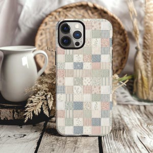 May include: A smartphone case featuring a patchwork design composed of small squares in soft pastel shades of pink, blue, green, and beige. The pattern includes various textures such as floral prints, gingham checks, stripes, and solid colors.