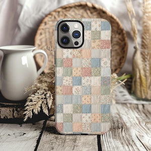May include: A smartphone case featuring a patchwork quilt design composed of small squares in soft pastel shades of blue, pink, peach, and green. The pattern includes various floral prints, gingham checks, and solid colors arranged in a grid.