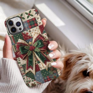 May include: A smartphone case featuring a patchwork design of holiday-themed squares in red, green, and cream. The pattern includes holly leaves, berries, pinecones, and stars. A large, central three-dimensional bow in red and green plaid sits on top.