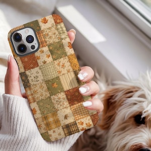 May include: A smartphone case featuring a patchwork design of various square patterns in shades of olive green, burnt orange, cream, and brown. The squares include motifs of small flowers, plaid, stripes, and scattered autumn maple leaves.