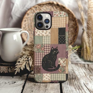 May include: A smartphone case featuring a patchwork design of various fabric patterns including floral prints, brown and white gingham, and solid colors. A black cat illustration is centered on the back, surrounded by the stitched quilt-like squares.