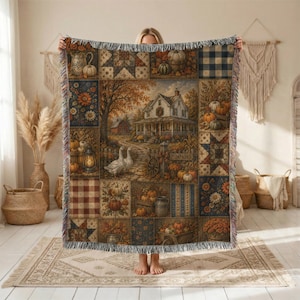 May include: A woven throw blanket featuring a patchwork design with autumn-themed scenes, including a farmhouse, geese, pumpkins, sunflowers, and plaid patterns. The blanket has a fringed edge and displays a warm color palette of orange, brown, and cream.