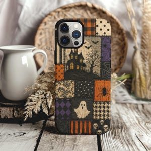May include: A smartphone case featuring a patchwork design with Halloween motifs including a haunted house, a ghost, a spider, skulls, bats, and various patterns like plaid, polka dots, and damask in black, orange, purple, and cream colors.