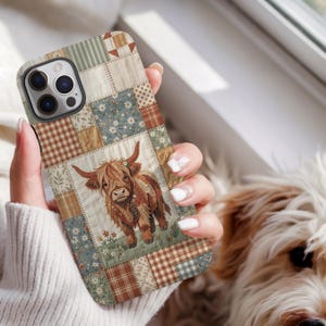 May include: A smartphone case featuring a patchwork quilt design with various squares in shades of brown, sage green, and cream. The central graphic depicts a brown Highland cow standing in a field of small flowers, surrounded by plaid and floral patterns.