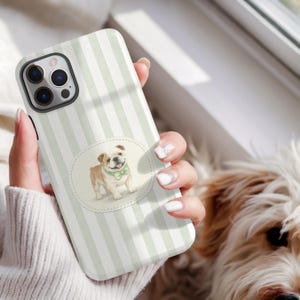 Peut inclure: Coque de téléphone à rayures blanches et vertes, ornée d'une illustration à l'aquarelle d'un bouledogue portant un nœud papillon vert. La coque possède une découpe pour l'appareil photo.