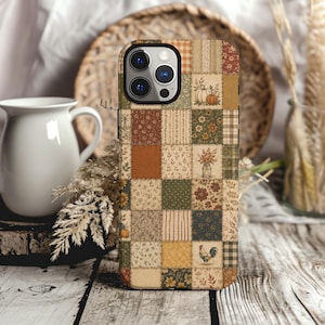 May include: A smartphone case featuring a patchwork design of various autumn-themed patterns, including pumpkins, floral prints, plaid, stripes, and a rooster illustration in shades of orange, brown, green, and cream with a black camera cutout.