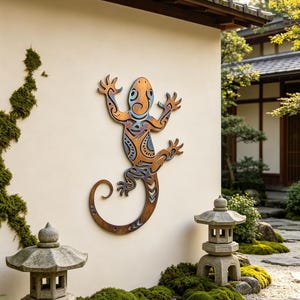 May include: A wooden lizard wall art piece with orange, blue, and brown tones, mounted on a cream-colored wall. The lizard has an intricate tribal design. The artwork is displayed in a Japanese garden setting, with stone lanterns and lush greenery.