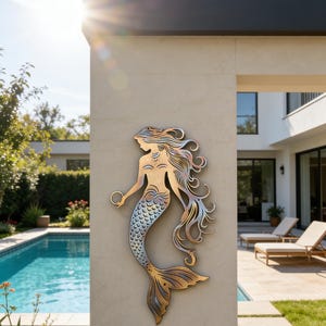 Könnte beinhalten: Metall-Wandskulptur einer Meerjungfrau mit Kupfer-, Silber- und Gold-Finish. Die Meerjungfrau hält einen Ring und hat fließendes Haar und einen geschuppten Schwanz. Die Skulptur ist an einer hellen Wand im Freien angebracht.