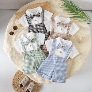 May include: Four sets of short-sleeved white shirts with matching gingham suspender shorts and bow ties in black, brown, sage green, and light blue. Each shirt features a button-down front, while the shorts have adjustable straps and cuffs.