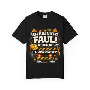May include: Black t-shirt with a graphic design featuring a construction-themed illustration. The design includes a hard hat, hammer, and the German text "ICH BIN NICHT FAUL! ICH BIN IM FEIERABENDMODUS."
