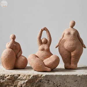 Pode incluir: Três esculturas de cor terracota de figuras humanas estilizadas em várias poses de ioga. As figuras têm uma superfície texturizada e são exibidas em uma superfície semelhante a pedra. As esculturas são um item decorativo.
