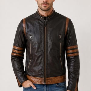 May include: A brown leather jacket with a stand-up collar, zip closure, and brown accents on the shoulders and sleeves. The jacket has three brown stripes on each sleeve and two zipped pockets on the chest. The model is wearing blue jeans.