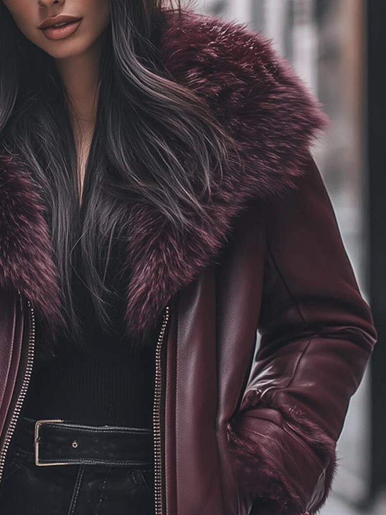 May include: A burgundy leather jacket with a faux fur collar and cuffs. The jacket features a zipper closure and a black belt with a silver buckle. The sleeves have fur trim, and the jacket appears to be worn over a black top.