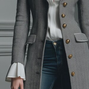Puede incluir: Un blazer gris con estampado de espiga con botones dorados y una blusa blanca. El blazer tiene un corte entallado con solapas de muesca y bolsillos con solapa. La blusa blanca tiene mangas acampanadas. El modelo lleva vaqueros azules.