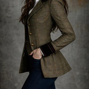 Pu&ograve; includere: Blazer in tweed marrone con colletto e polsini in velluto scuro. Il blazer ha bottoni dorati e una vestibilit&agrave; su misura. La persona indossa una camicia bianca e jeans blu scuro. Stile classico.