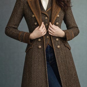 May include: A brown herringbone tweed coat with a matching vest and gold buttons. The coat has a tailored fit with a notched collar and brown trim. The model is wearing a white blouse and blue jeans.