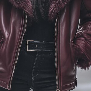 May include: A burgundy leather jacket with a faux fur collar and cuffs. The jacket features a zipper closure and a black belt. The model is wearing black jeans.