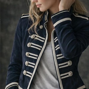 May include: Navy blue velvet jacket with white trim and silver buttons. The jacket has a military-inspired design with decorative stripes on the sleeves and front. A stylish piece of outerwear.