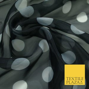 May include: Black sheer fabric with large white polka dots. The fabric is draped, creating folds and shadows. The material has a slight sheen, and the polka dots are evenly spaced across the surface. The Textile Plaza logo is in the bottom right corner.
