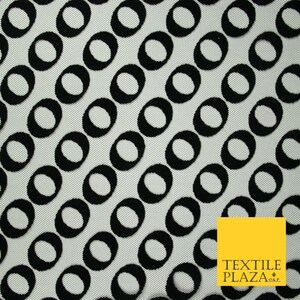 May include: A fabric featuring a repeating pattern of black oval shapes set against a white background. The ovals are arranged diagonally. A yellow square with the text "TEXTILE PLAZA O&P" is in the corner.