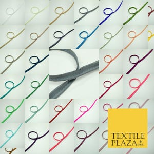 May include: A selection of colourful piping cords in a grid arrangement, including white, beige, brown, black, blue, green, and pink. A close-up of a grey piping cord is in the centre. The Textile Plaza logo is visible.