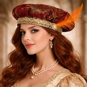 May include: A Renaissance-style hat with a burgundy and gold brocade pattern, trimmed with gold lace and an orange feather. The hat is adorned with a pearl and gold embellishment. The image also shows a pearl necklace and earrings.