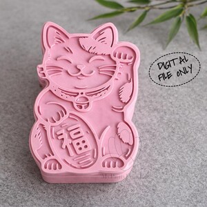 May include: A pink Maneki Neko cat figurine with a raised paw, collar, and a coin with Chinese characters. The image includes the text "DIGITAL FILE ONLY" in a circular shape. The cat is a symbol of good luck and fortune.