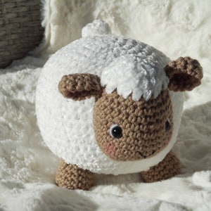 May include: A white crocheted plush lamb with brown crocheted facial features and a fluffy white body.