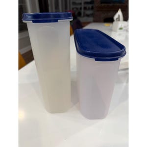 Könnte beinhalten: Zwei transparente, rechteckige Lebensmittelbehälter mit dunkelblauen Deckeln. Die Behälter bestehen aus einem durchscheinenden Kunststoffmaterial. Ein Behälter ist höher als der andere. Die Behälter stehen auf einer weißen Oberfläche.