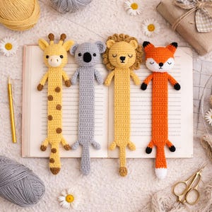 以下が含まれることがあります： 手作りのかぎ針編み動物ブックマーク4点：キリン、コアラ、ライオン、キツネ。キリンは黄色に茶色の斑点、コアラはグレー、ライオンは黄色のたてがみ、キツネはオレンジ色に白いお腹。各ブックマークは細長い長方形の形をしています。