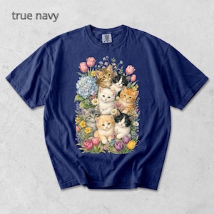 Puede incluir: Camiseta azul marino con una ilustraci&oacute;n de acuarela de gatitos y flores. Los gatitos son de varios colores, incluyendo naranja, gris y blanco. El texto "true navy" est&aacute; en la parte superior izquierda.