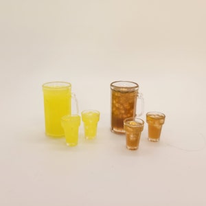May include: Two glass pitchers, one filled with yellow lemonade and the other with brown iced tea, with four clear glasses filled with the same beverages.