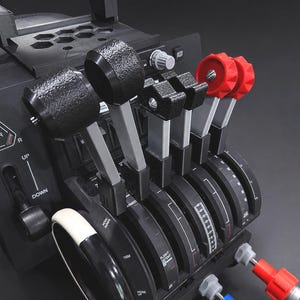 May include: A black flight simulator throttle quadrant with multiple levers and knobs. The unit features black and red controls, with labels for gear and trim. The design includes a gear selector and various levers for flight control.