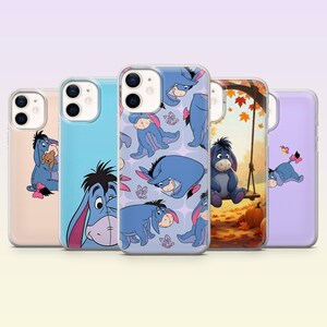 May include: Five clear phone cases featuring Eeyore from Winnie the Pooh. Designs include Eeyore with a teddy bear, a close-up face, a repeating pattern with butterflies, Eeyore sitting on a swing in autumn leaves, and Eeyore with a butterfly.